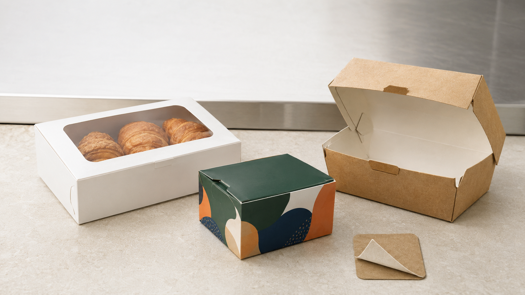 Printed bakery, frozen-food, and takeout boxes made from paperboard with food-contact barrier components.